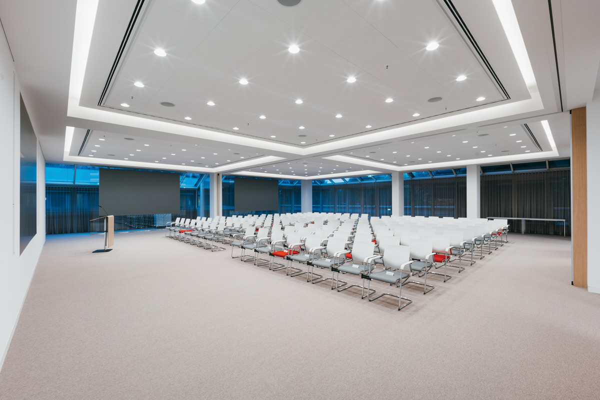 The auditorium is a rectangle, which can be partitioned to enable different settings. The white Sito cantilever chairs (design: wiege) with gray and the occasional red covers indicate the Sparkasseﾒs corporate design.